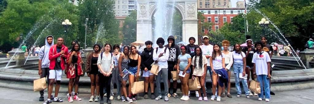 a group of teenagers in front of a fountain.