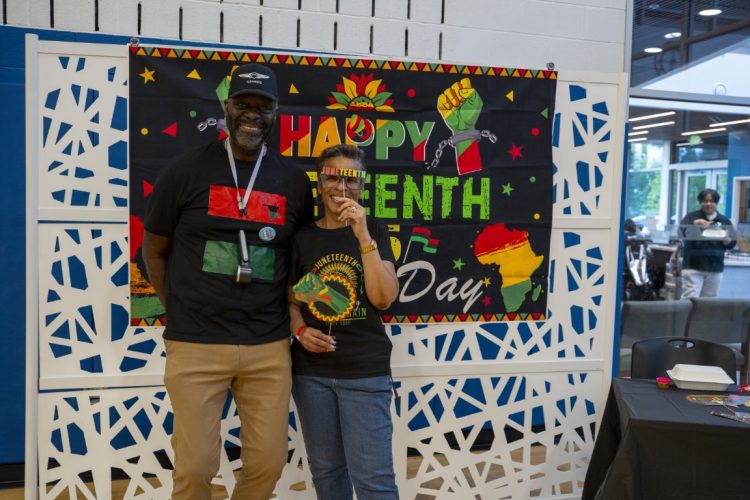 woman and man posing in front of juneteenth sign