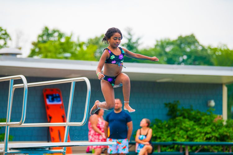 Young girls jumping into in the Springfield YMCA Community Pool off diving board